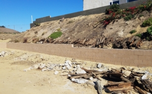 Eroded hillside with debris and retaining wall